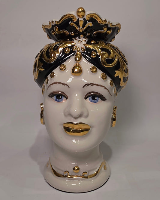 Coppia di Teste di Moro in ceramica artigianale bianca lucida con turbanti neri riccamente decorati da fregi e dettagli in oro zecchino. Queste sculture ornamentali raffiguranti un uomo con baffi e una donna con labbra dorate sono complementi d'arredo di lusso che reinterpretano la tradizione siciliana in chiave moderna ed elegante.