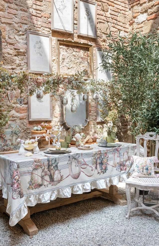 Runner da tavola della linea "Joyeuses Paques" caratterizzato da un'elegante trama a righe verticali beige e azzurre con decorazioni d'ispirazione vintage. Il pannello centrale nei toni del rosa racchiude una raffinata illustrazione pasquale con un coniglietto dentro un cesto intrecciato, uova colorate e rose, ideale per apparecchiare la tavola delle feste in perfetto stile shabby chic.