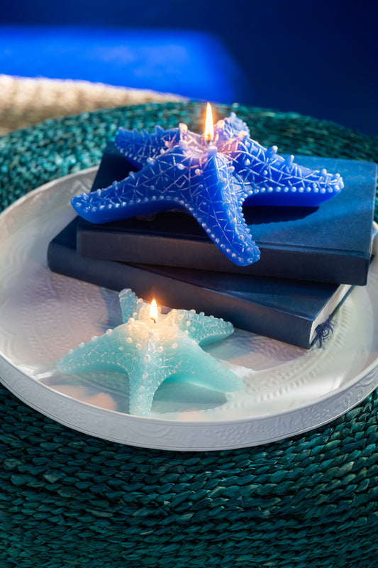 Candela a forma di stella marina piccola azzurra firmata Jolipa, perfetta come elemento decorativo e centrotavola per una casa in stile marino o costiero. Il complemento d'arredo presenta dettagli realistici in rilievo con sfumature bianche ed è fotografato su un fondo bianco isolato.