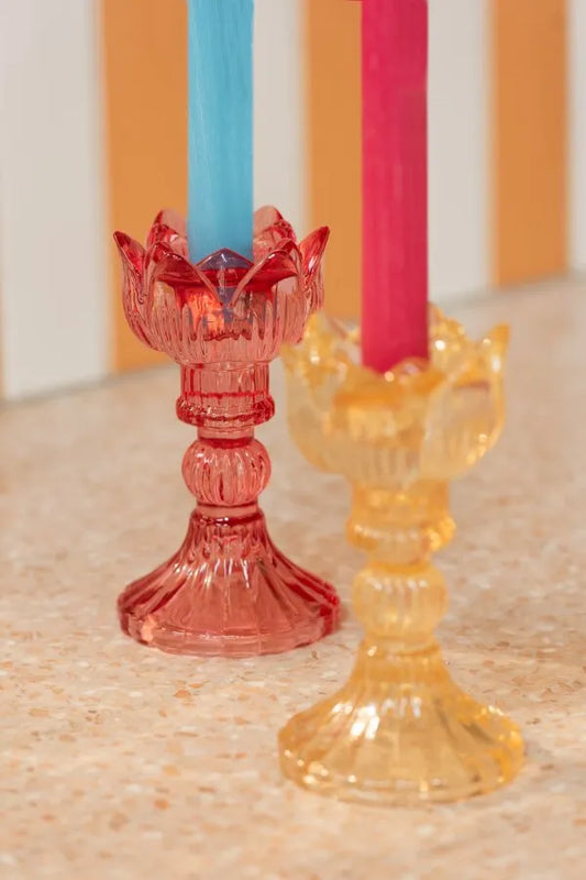 Portacandele a forma di tulipano in vetro colorato assortiti, caratterizzati da una sommità modellata a petali aperti e uno stelo decorativo scanalato che termina su una base conica lavorata a rilievo. Disponibili nelle tre varianti trasparente rosa, crema e rosso, questi eleganti candelabri di design sono ideali per sorreggere candele a stelo lungo, arricchire la tavola e donare un tocco di luce raffinato e primaverile all'home decor.