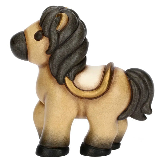 Statuina in ceramica del cavallo Isabella di piccole dimensioni firmata THUN, caratterizzata da un corpo nei toni caldi del beige con criniera, coda e zoccoli scuri sfumati. La figura da collezione presenta forme dolci e arrotondate tipiche del marchio, arricchita da una sella color panna con dettagli dorati sul dorso che la rende un'ottima idea regalo o un elemento decorativo per la casa.
