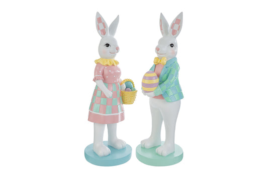 Coppia di statuine decorative a forma di conigli bianchi in piedi su basi circolari color pastello. La coniglietta indossa un abito rosa a pois con gonna a scacchi verdi e tiene un cestino di uova; il coniglio indossa una giacca a scacchi azzurri e verdi con papillon giallo e regge un uovo decorato. Design in stile MacKenzie-Childs per il marchio Le Stelle.