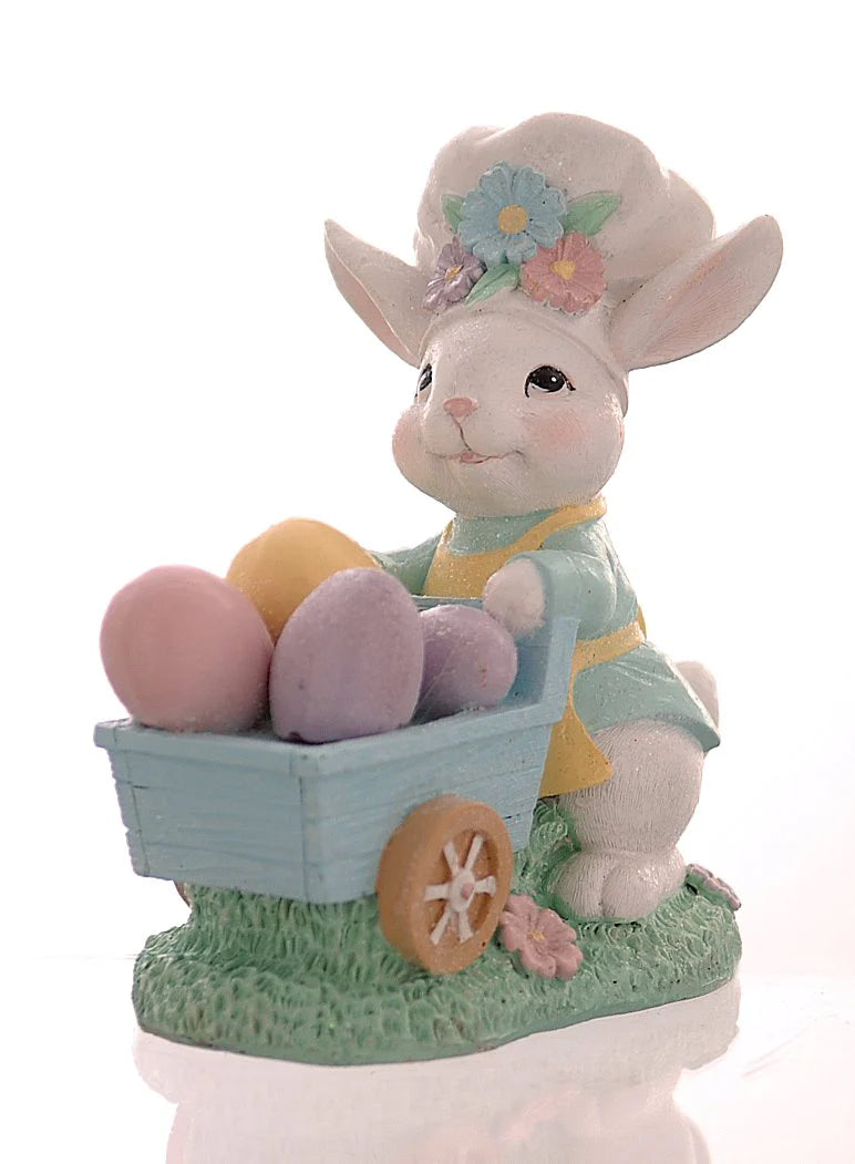 Decorazione pasquale Vetur in poliresina h 16 cm. Personaggio coniglio bianco vestito con giacca azzurra e pantaloni verdi che trasporta una pila di uova di Pasqua colorate e decorate con fiori.