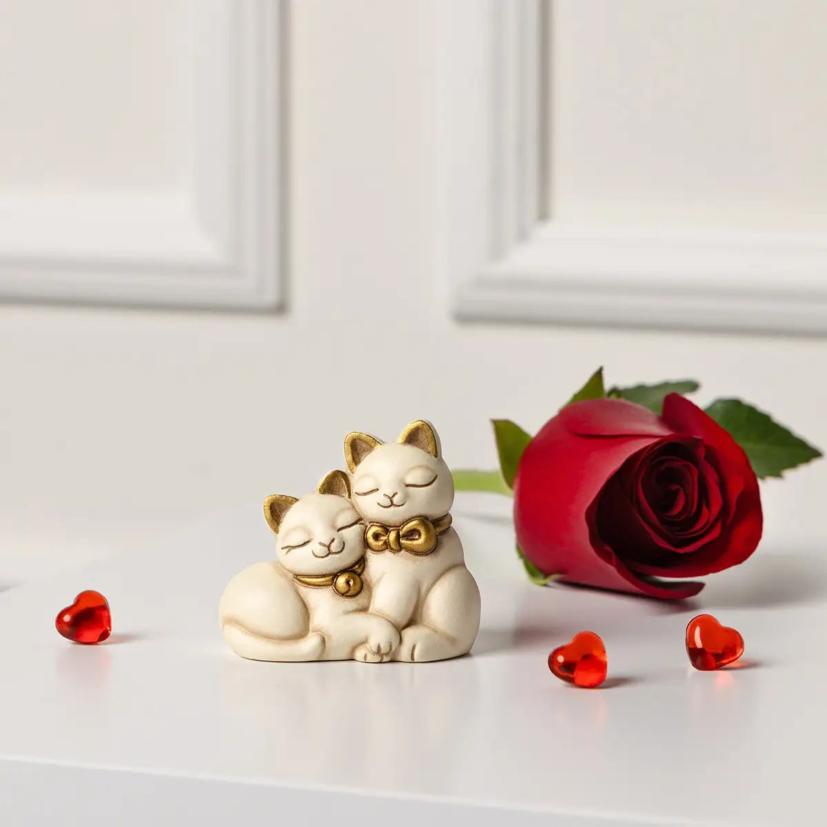 L'immagine ritrae la statuetta dei gattini sorridenti inserita in un contesto romantico e minimalista, perfetta per illustrare un'idea regalo o un complemento d'arredo per occasioni speciali.