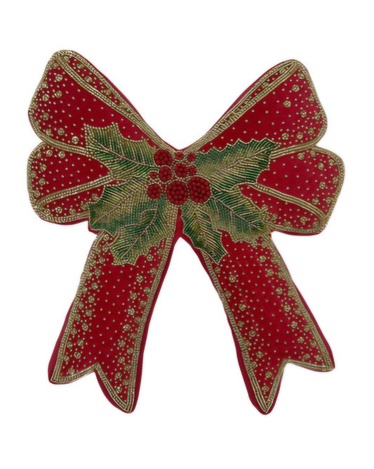 Cuscino decorativo a forma di fiocco natalizio in velluto rosso con ricami dorati, bacche rosse a rilievo e foglie di agrifoglio verdi al centro. Design sagomato elegante su sfondo bianco.