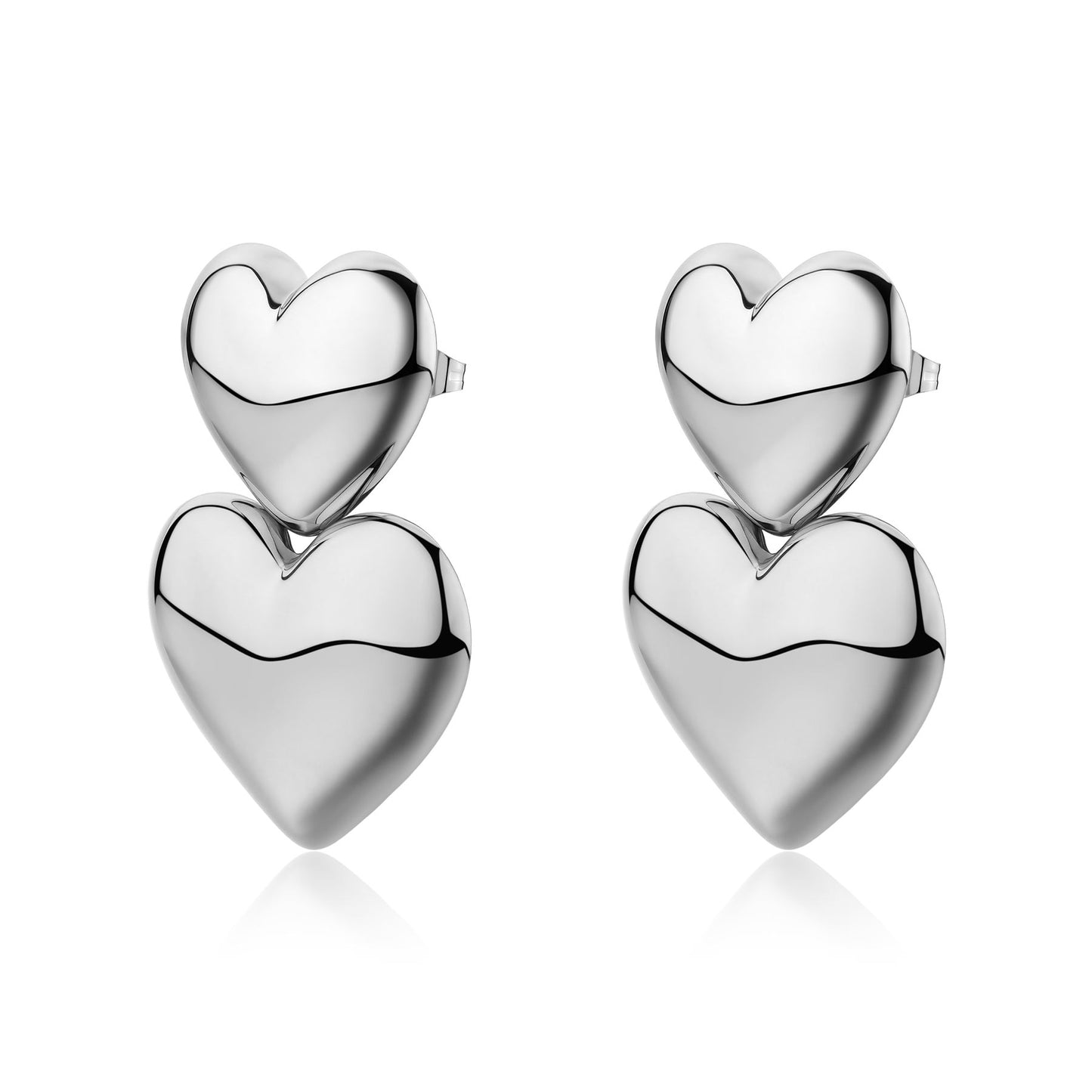 Orecchini a lobo in acciaio 316L lucido composti da due cuori bombati sovrapposti. Il cuore superiore, più piccolo, sostiene un secondo cuore pendente più grande, entrambi con finitura silver specchiata.