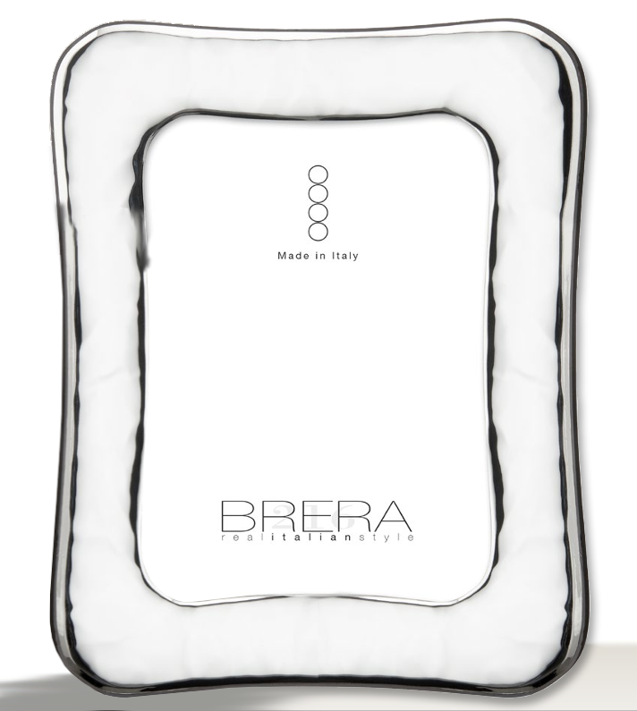 Portafoto da tavolo in argento bilaminato lucido con cornice sagomata e profilo ondulato. La superficie è caratterizzata da una lavorazione "stropicciata" o a effetto martellato morbido che crea riflessi luminosi dinamici. L'inserto centrale bianco riporta il marchio "BRERA real italian style" e la certificazione "Made in Italy".