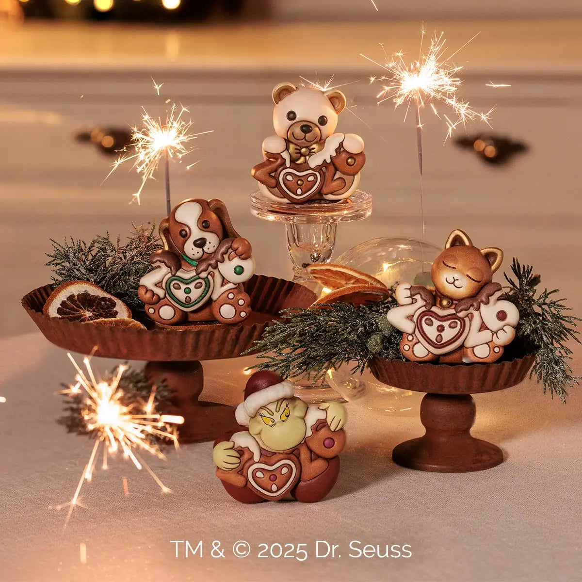 Un'immagine fotografica ambientata che mostra una collezione di quattro statuette decorative disposte su diversi livelli. Al centro, in alto su un'alzatina di vetro trasparente, spicca l'orsetto Teddy che tiene la scritta "2026".