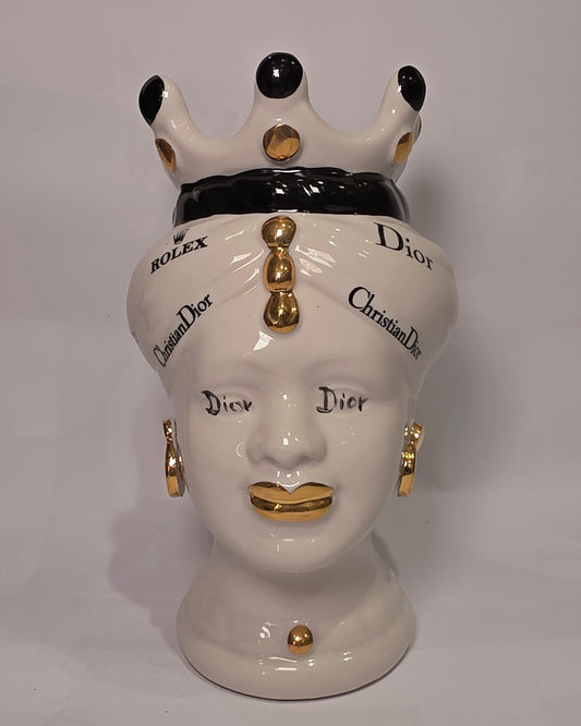 Coppia di Teste di Moro in ceramica bianca lucida con turbanti neri e bianchi decorati da loghi fashion neri e dorati, completate da corone regali e labbra con finitura in oro zecchino. Queste sculture ornamentali di design pop art fondono la tradizione ceramica siciliana con l'estetica del lusso moderno, rappresentando un complemento d'arredo audace ed esclusivo per interni ricercati.