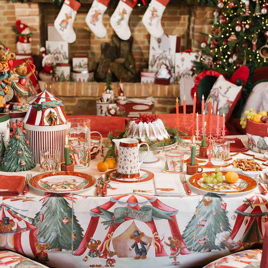 Tavola natalizia imbandita con la tovaglia "Bear Wonderland", piatti coordinati, candelabri rossi e decorazioni a tema orsetti in un ambiente caldo davanti a un camino.