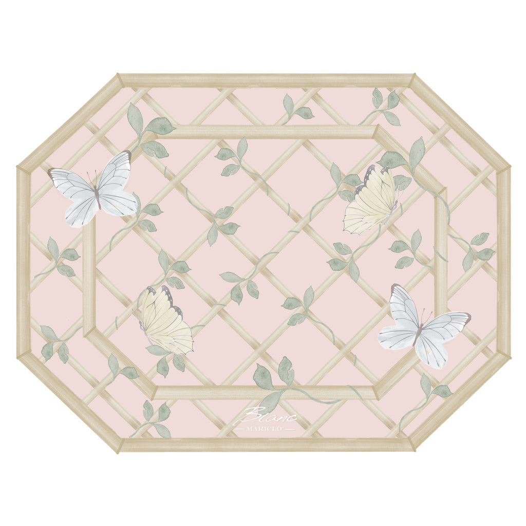 Tovaglietta americana ottagonale Blanc Mariclò collezione "Floral Twist". Il design presenta un fondo rosa cipria con una grata in legno illustrata su cui si posano farfalle bianche e gialle tra foglie verdi delicate.