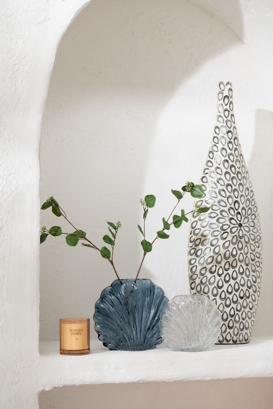 Vaso decorativo in vetro trasparente a forma di conchiglia della collezione "Oceano Azul" di Jolipa, caratterizzato da una superficie lavorata con scanalature verticali a rilievo che riflettono la luce. Questo originale complemento d'arredo di ispirazione marina è ideale per ospitare fiori freschi o come elegante centrotavola per impreziosire gli ambienti di casa.