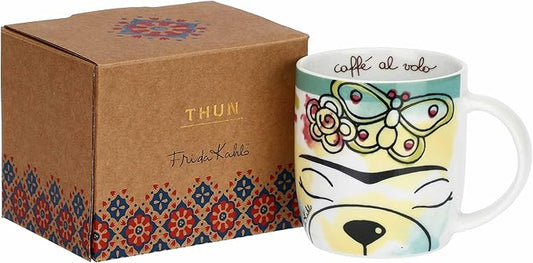 Questa mug in porcellana della collezione THUN x Frida Kahlo unisce la tenerezza del classico Teddy THUN alla forza espressiva dell'artista messicana. Il decoro centrale ritrae il celebre orsetto con l'iconica corona di fiori e uno stile ispirato ai dipinti di Frida, circondato da farfalle e fiori variopinti su un fondo bianco luminoso. Realizzata in porcellana di alta qualità, questa tazza è un pezzo da collezione ideale per chi desidera una colazione che celebri l'arte