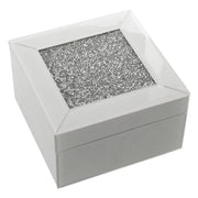Portagioie quadrato in vetro bianco lucido con coperchio incorniciato e centro interamente ricoperto di brillantini argentati sfaccettati. Scatola portagioie elegante firmata E-Camacho, ideale come oggetto d'arredo glamour o idea regalo raffinata.
