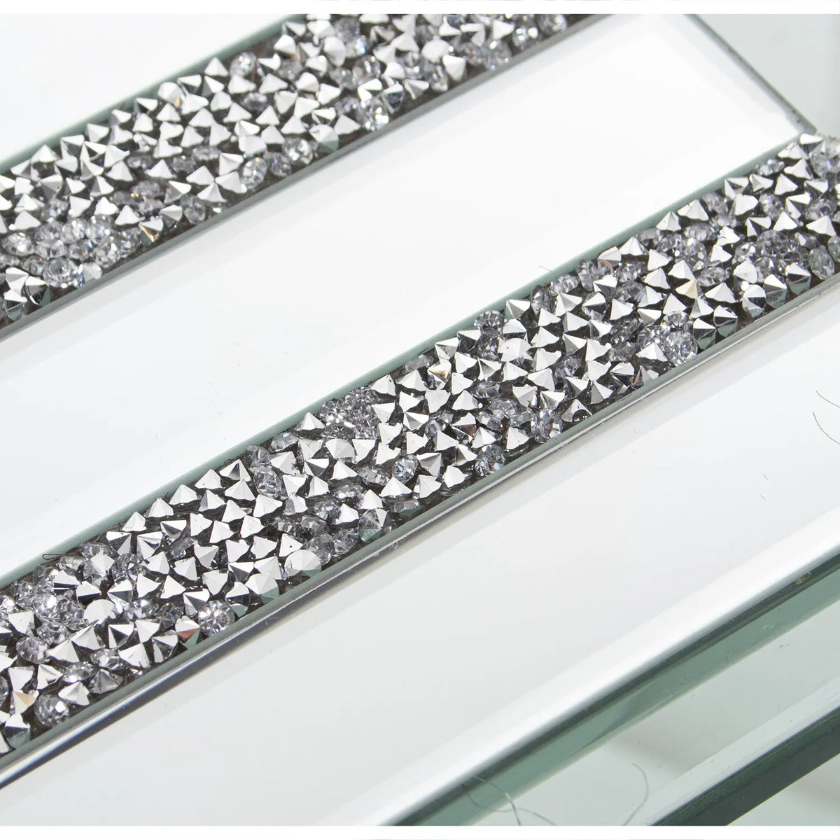 Portagioie rettangolare in vetro specchiato con coperchio attraversato da tre fasce parallele interamente incastonate di brillantini trasparenti sfaccettati. Scatola portagioie elegante firmata E-Camacho, ideale come oggetto d'arredo glamour o idea regalo raffinata.