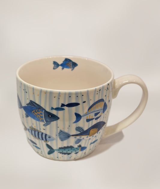 Tazza mug in ceramica bianca firmata Efya, impreziosita da una decorazione artistica a tema marino con pesciolini dipinti in varie sfumature di blu, azzurro e dettagli gialli. La superficie esterna presenta uno sfondo a delicate righe verticali azzurre con piccoli pois, mentre un ulteriore pesce decorativo è visibile sul bordo interno, rendendola un'idea regalo ideale o un perfetto complemento per la colazione estiva.