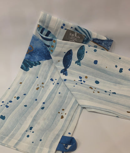 Strofinaccio da cucina in puro cotone del marchio Efya, caratterizzato da una fantasia marina con pesciolini decorativi stampati in varie tonalità di blu e azzurro. Il canovaccio presenta uno sfondo a righe verticali sfumate arricchito da piccoli pois e include una pratica asola blu nell'angolo inferiore per appenderlo comodamente.