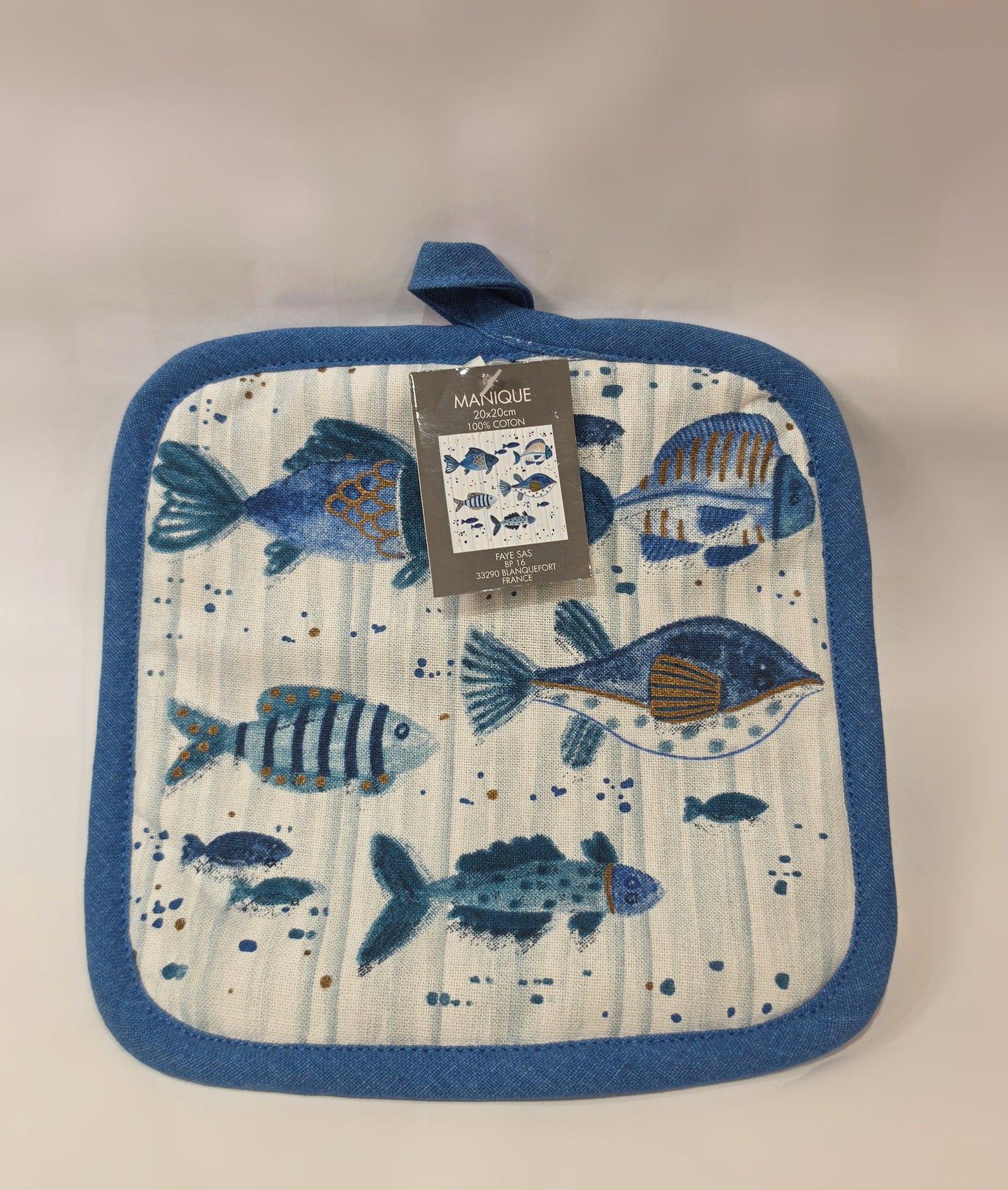 Presina da cucina quadrata in cotone caratterizzata da una fantasia a tema marino con pesciolini stampati in varie tonalità di blu, azzurro e dettagli ocra. Il tessile presenta uno sfondo a righe verticali sfumate, un bordo perimetrale blu e una pratica asola superiore per appenderla comodamente in cucina.
