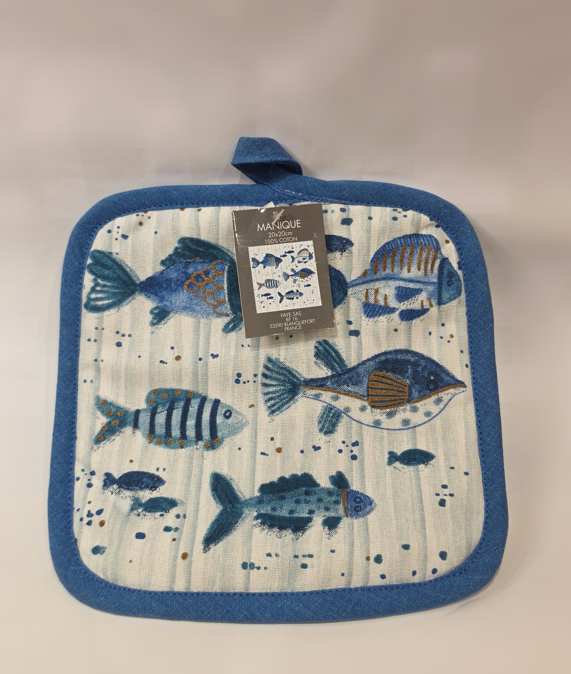 Presina da cucina quadrata in cotone caratterizzata da una fantasia a tema marino con pesciolini stampati in varie tonalità di blu, azzurro e dettagli ocra. Il tessile presenta uno sfondo a righe verticali sfumate, un bordo perimetrale blu e una pratica asola superiore per appenderla comodamente in cucina.