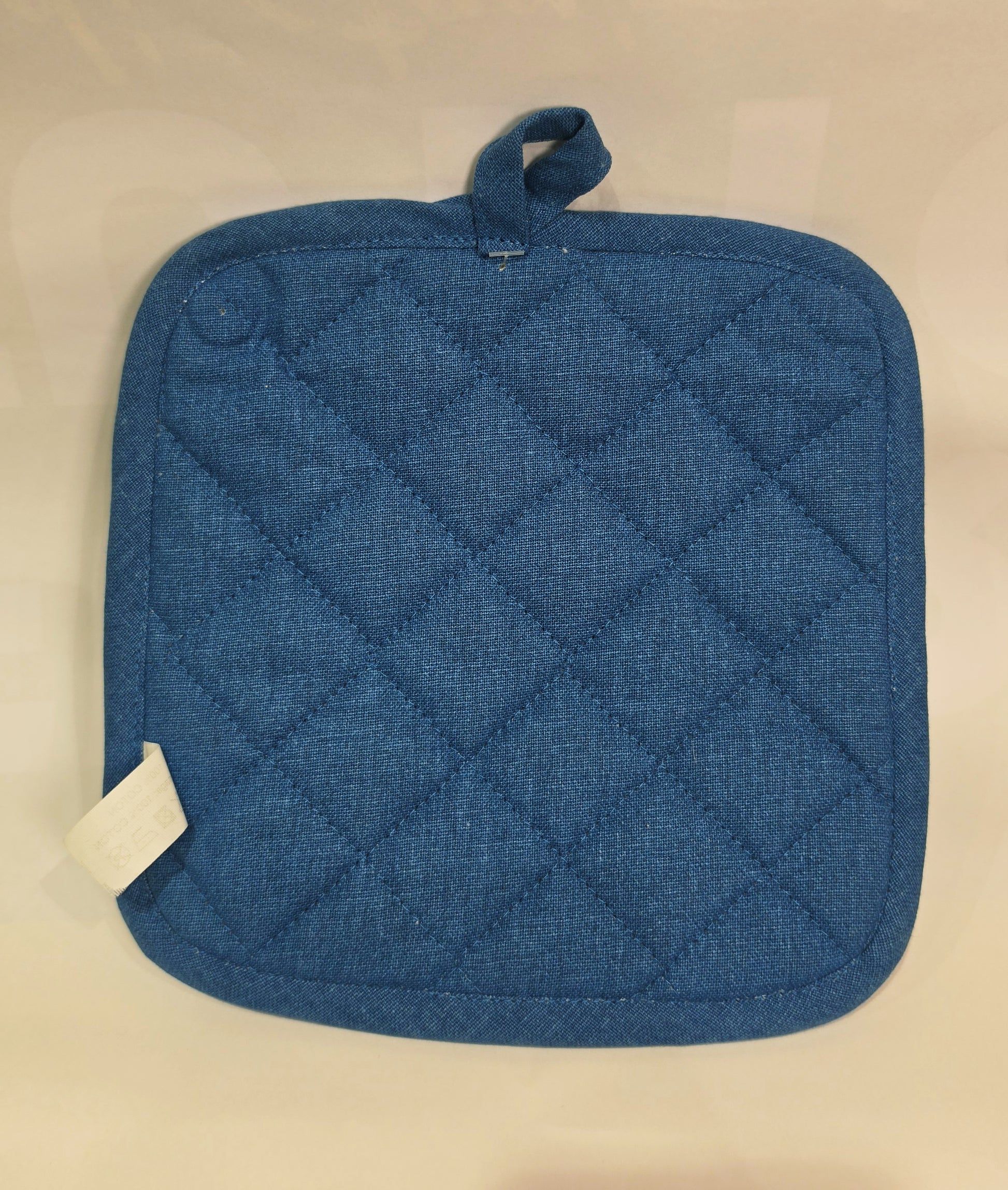 Presina da cucina quadrata in cotone caratterizzata da una fantasia a tema marino con pesciolini stampati in varie tonalità di blu, azzurro e dettagli ocra. Il tessile presenta uno sfondo a righe verticali sfumate, un bordo perimetrale blu e una pratica asola superiore per appenderla comodamente in cucina.
