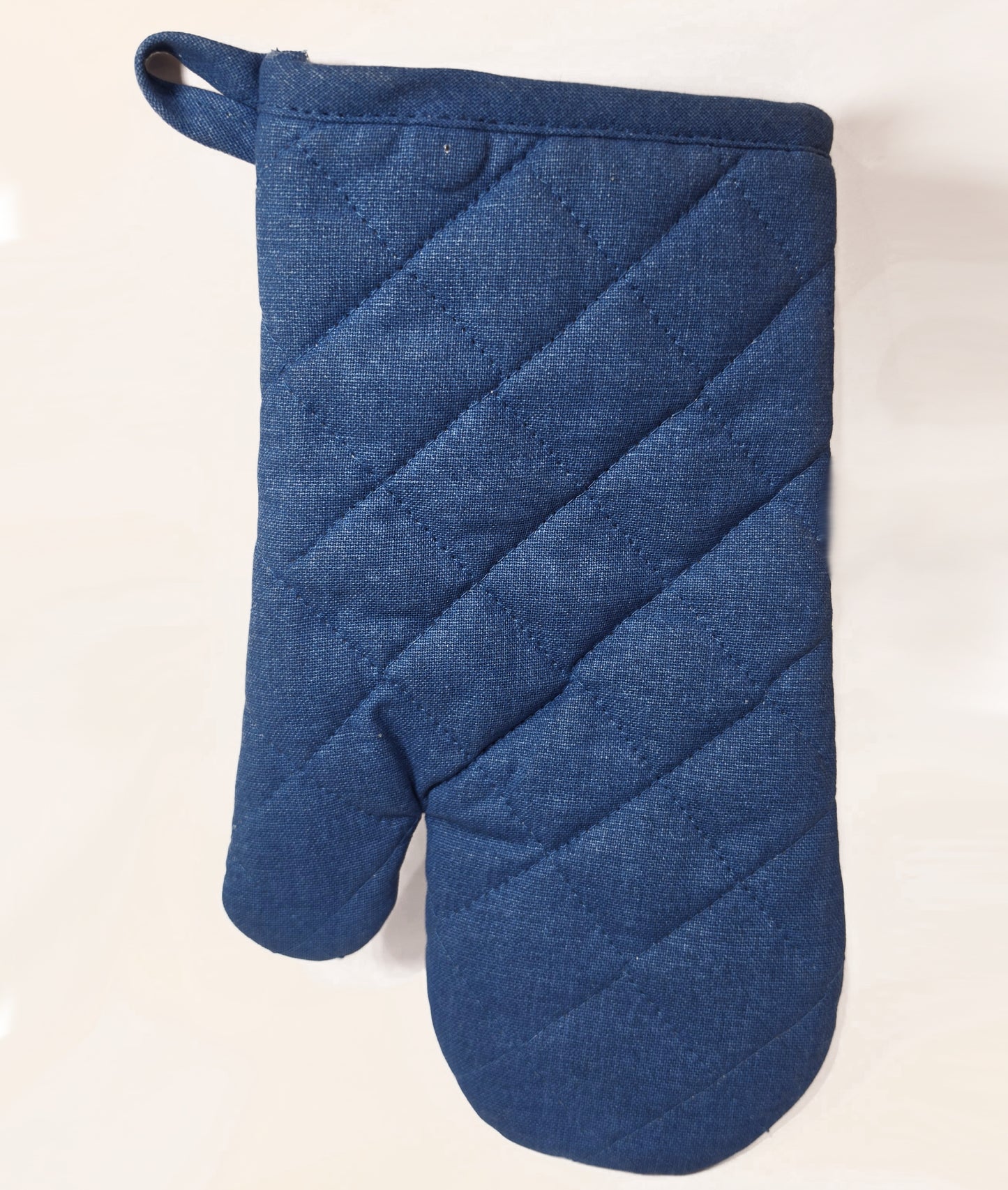 Guantone da cucina in cotone caratterizzato da una fantasia a tema marino con pesciolini stampati in varie tonalità di blu, azzurro e dettagli ocra. Il tessile presenta uno sfondo a righe verticali sfumate e un bordo superiore blu con asola per appenderlo, perfetto per proteggere le mani con stile durante la preparazione dei piatti.