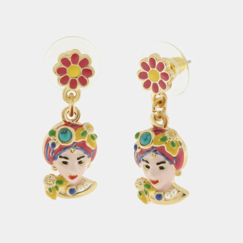 Orecchini pendenti dorati della collezione Etna caratterizzati da un lobo a forma di fiore rosa e giallo e un charm a Testa di Moro finemente smaltato. Il design artigianale presenta dettagli vivaci in rosa, rosso e verde con piccole applicazioni luminose che richiamano la tradizione folk siciliana. Questi orecchini con Testa di Moro rosa e fiori sono l'accessorio perfetto per aggiungere un tocco di colore e cultura mediterranea a un outfit moderno e originale.