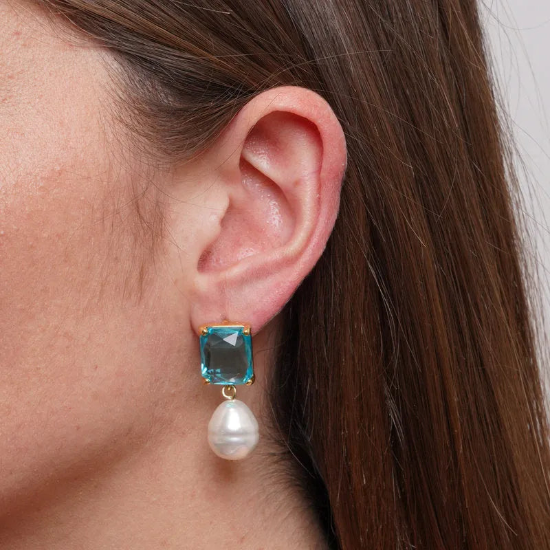 Orecchini a lobo con cristallo rettangolare sfaccettato azzurro e perla bianca a goccia pendente, su base dorata. Gioiello elegante, ideale per occasioni speciali e come idea regalo.