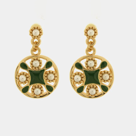 Orecchini pendenti dorati della collezione Fiori di Lava con design a maiolica rotonda, decorati da smalto verde scuro e perle bianche incastonate. La struttura traforata richiama l'estetica mediterranea, abbinando un lobo a fiore con perla a un medaglione geometrico raffinato. Questi orecchini con maiolica verde e perle sono l'accessorio ideale per un look elegante e d'ispirazione artigianale.
