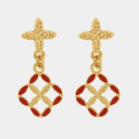 Orecchini pendenti dorati della collezione Fiori di Lava con design a maiolica rossa e attacco a perno a forma di fiore testurizzato. Il ciondolo a quadrifoglio traforato presenta bordi smaltati in un vivace rosso corallo che incorniciano un dettaglio centrale in metallo dorato lavorato. Questi orecchini con maiolica rossa fondono perfettamente l'ispirazione siciliana e lo stile contemporaneo, ideali per chi cerca un gioiello artigianale distintivo.