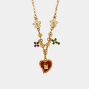 Collana BySimon della collezione Sacro con catena dorata, pendente centrale a Cuore Sacro rosso con corona e charm laterali a forma di croci colorate e fiori bianchi.