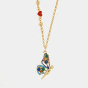 Collana BySimon della collezione Favignana con catena dorata a maglie circolari, caratterizzata da un pendente centrale a forma di farfalla multicolore smaltata e un piccolo charm a cuore rosso laterale.
