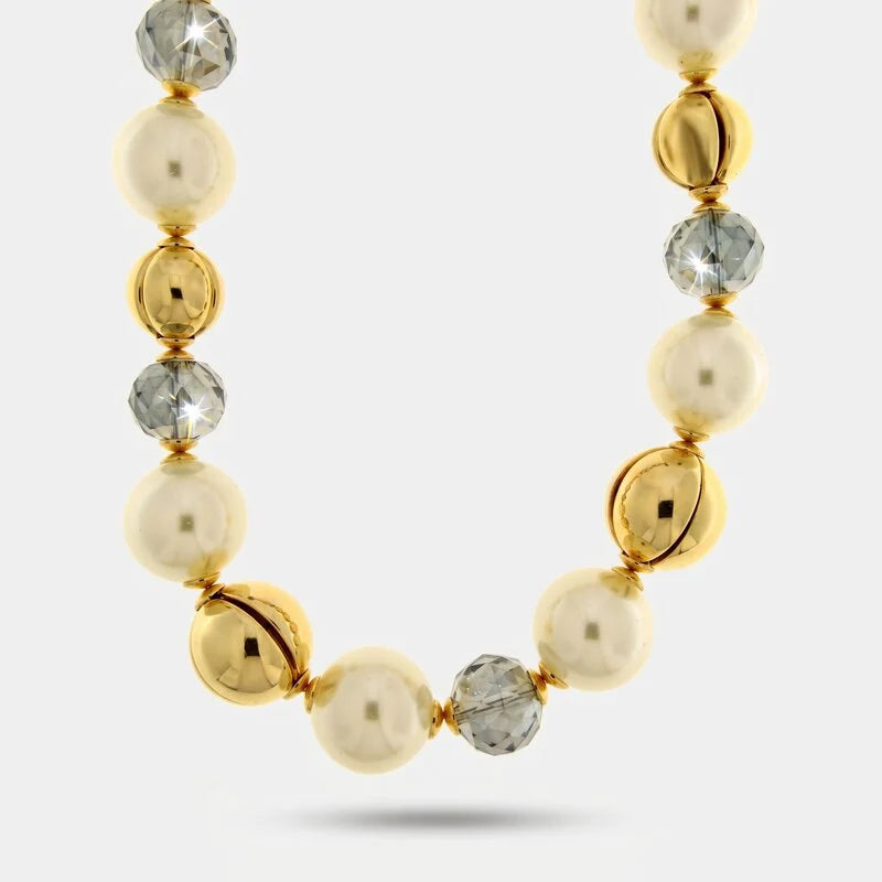 Collana con perle bianche classiche, sfere lisce dorate e cristalli sfaccettati grigio trasparente alternati. Gioiello scenografico e luminoso, ideale per occasioni speciali e come idea regalo.