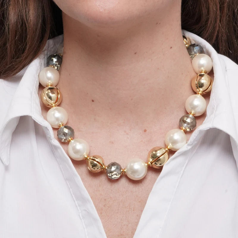Collana con perle bianche classiche, sfere lisce dorate e cristalli sfaccettati grigio trasparente alternati. Gioiello scenografico e luminoso, ideale per occasioni speciali e come idea regalo.