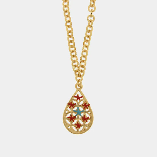 Collana in metallo con finitura dorata del marchio BySimon appartenente alla collezione Fiori di Lava caratterizzata da una catena a maglia rolo con un pendente a forma di goccia traforata. Il ciondolo presenta un raffinato motivo a intreccio che ospita sette piccole stelle marine tridimensionali smaltate, di cui sei di un rosso vivace disposte circolarmente e una centrale in colore azzurro a contrasto. La struttura lucida della collana e il design ispirato alla natura marina rendono questo gioiello un acce