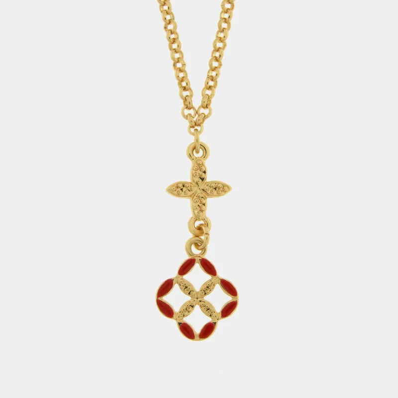 Collana con catena dorata e pendente Fiori di Lava su fondo bianco neutro. Il ciondolo è composto da un elemento dorato a croce filigranata e un ciondolo floreale stilizzato smaltato rosso e oro. L'accessorio appartiene alla collezione Maiolica Rossa di Fiori di Lava.