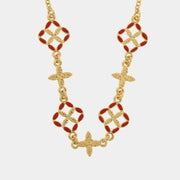 Questa elegante collana dorata della collezione Fiori di Lava firmata bysimon presenta un design raffinato con pendenti a forma di maioliche smaltate in un vivace rosso corallo. L'alternanza tra i motivi floreali traforati e i piccoli charms a croce in metallo dorato testurizzato rende questo gioiello un accessorio dallo stile mediterraneo unico e sofisticato. Perfetta per impreziosire ogni outfit, la collana bysimon con maioliche rosse celebra l'artigianato d'ispirazione siciliana 
