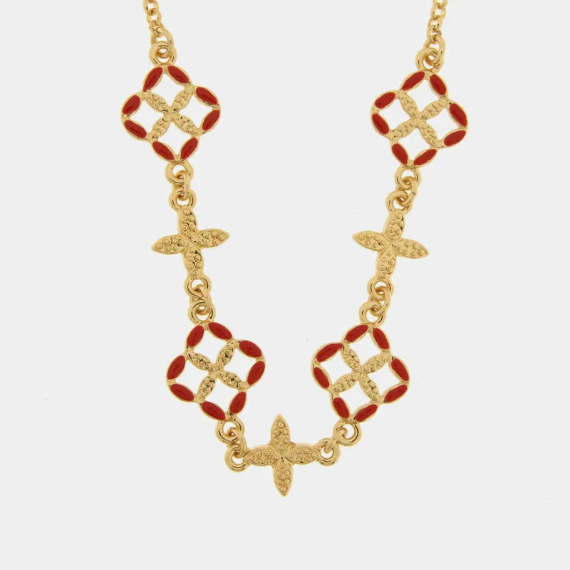 Questa elegante collana dorata della collezione Fiori di Lava firmata bysimon presenta un design raffinato con pendenti a forma di maioliche smaltate in un vivace rosso corallo. L'alternanza tra i motivi floreali traforati e i piccoli charms a croce in metallo dorato testurizzato rende questo gioiello un accessorio dallo stile mediterraneo unico e sofisticato. Perfetta per impreziosire ogni outfit, la collana bysimon con maioliche rosse celebra l'artigianato d'ispirazione siciliana 