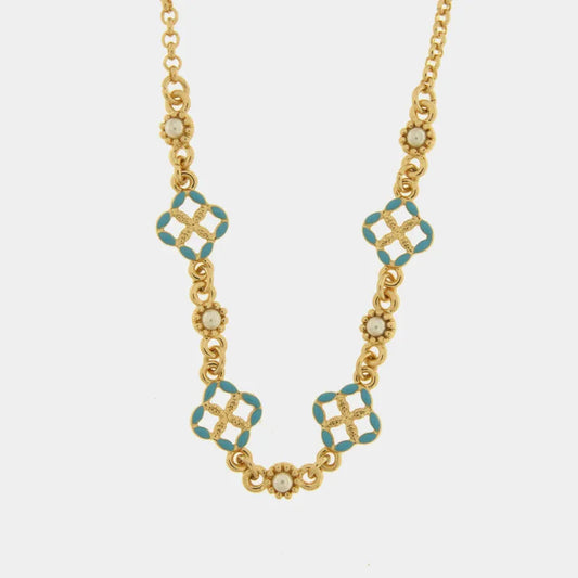 Questa collana a catena dorata firmata Fiori di Lava bysimon presenta un design elegante con maglie circolari e decorazioni alternate. Il gioiello è impreziosito da charms a forma di maiolica quadrilobata con smalto azzurro e piccoli inserti floreali dorati con perla centrale. Questa raffinata collana con maioliche azzurreè ritratta su un fondo chiaro per esaltarne i dettagli artigianali e i riflessi dell'oro.