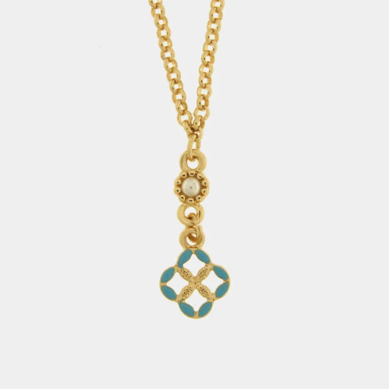 Collana in metallo con finitura dorata del marchio BySimon appartenente alla collezione Fiori di Lava caratterizzata da una sottile catenina a maglia rolo che sostiene un pendente centrale a forma di quadrifoglio traforato. Il ciondolo è ispirato alle tradizionali maioliche siciliane e presenta petali rifiniti in smalto azzurro brillante con una lavorazione dorata a rilievo nel cuore del decoro.