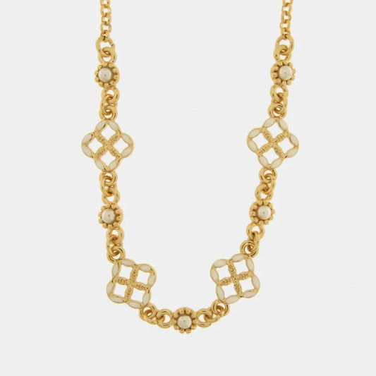 Questa collana a catena dorata firmata Fiori di Lava bysimon presenta un design elegante con maglie circolari e decorazioni alternate. Il gioiello è impreziosito da charms a forma di maiolica quadrilobata con smalto bianco e piccoli inserti floreali dorati con perla centrale. Questa raffinata collana con maioliche bianche è ritratta su un fondo chiaro per esaltarne i dettagli artigianali e i riflessi dell'oro.