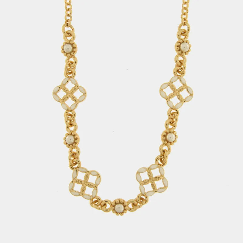 Questa collana a catena dorata firmata Fiori di Lava bysimon presenta un design elegante con maglie circolari e decorazioni alternate. Il gioiello è impreziosito da charms a forma di maiolica quadrilobata con smalto bianco e piccoli inserti floreali dorati con perla centrale. Questa raffinata collana con maioliche bianche è ritratta su un fondo chiaro per esaltarne i dettagli artigianali e i riflessi dell'oro.