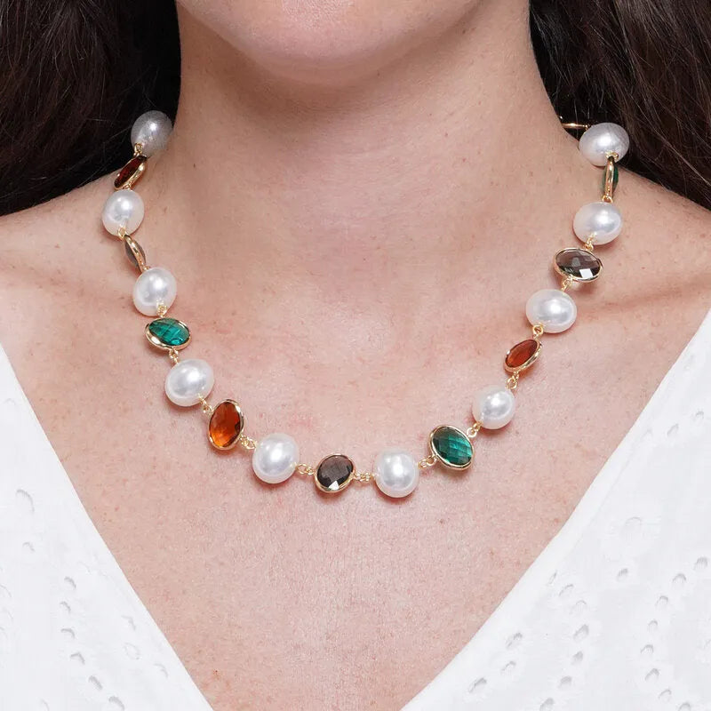 Collana con perle bianche classiche e cristalli ovali sfaccettati nei colori nero, verde smeraldo e ambra, incastonati in metallo dorato. Gioiello scenografico, ideale per occasioni speciali e come idea regalo.
