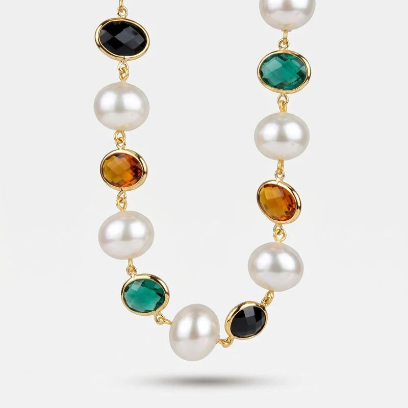 Collana con perle bianche classiche e cristalli ovali sfaccettati nei colori nero, verde smeraldo e ambra, incastonati in metallo dorato. Gioiello scenografico, ideale per occasioni speciali e come idea regalo.