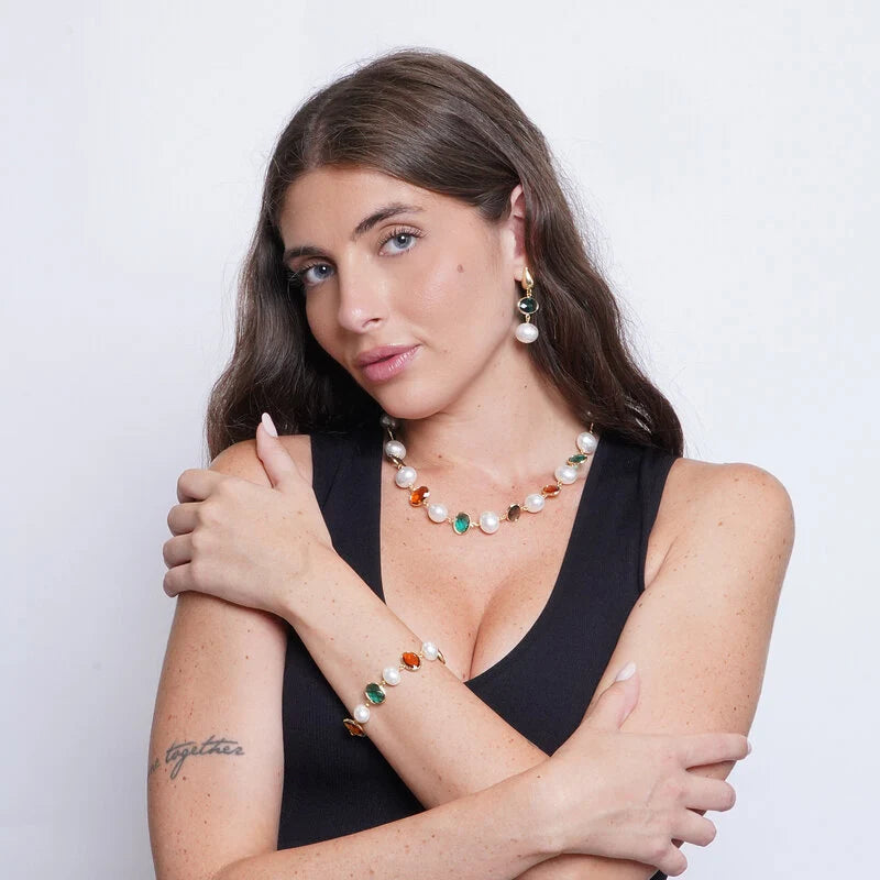 Collana con perle bianche classiche e cristalli ovali sfaccettati nei colori nero, verde smeraldo e ambra, incastonati in metallo dorato. Gioiello scenografico, ideale per occasioni speciali e come idea regalo.