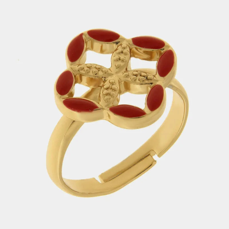 Anello regolabile in metallo con finitura dorata del marchio BySimon appartenente alla collezione Fiori di Lava caratterizzato da un castone centrale a forma di quadrifoglio stilizzato che richiama i decori della Maiolica. Il gioiello è impreziosito da smalto rosso applicato sui petali esterni e presenta un motivo a rilievo finemente lavorato nella parte centrale della struttura superiore. La fascia dell'anello è lucida e aperta sul retro per permettere di adattare facilmente la misura al dito, rendendo