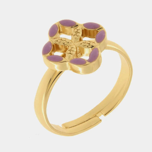 Anello regolabile in metallo con finitura dorata del marchio BySimon appartenente alla collezione Fiori di Lava caratterizzato da un castone centrale a forma di quadrifoglio stilizzato che richiama i decori della Maiolica. Il gioiello è impreziosito da smalto viola applicato sui petali esterni e presenta un motivo a rilievo finemente lavorato nella parte centrale della struttura superiore. La fascia dell'anello è lucida e aperta sul retro per permettere di adattare facilmente la misura al dito, rendendo