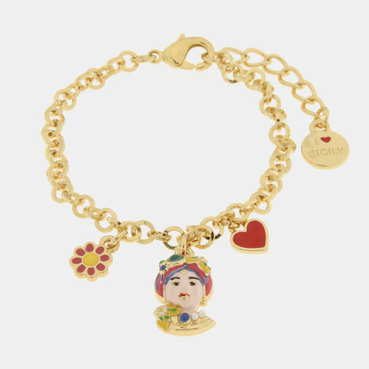 Questo bracciale dorato della collezione Etna presenta un vivace pendente a forma di Testa di Moro rifinito con smalti rosa e dettagli multicolore. La catena a maglie tonde è arricchita da charms smaltati che raffigurano un cuore rosso e un fiorellino, richiamando la tradizione siciliana in chiave contemporanea. Completo di chiusura a moschettone regolabile e medaglietta "I Love Sicily", questo bracciale con Testa di Moro rosa è un gioiello artigianale perfetto per un look allegro e sofisticato.