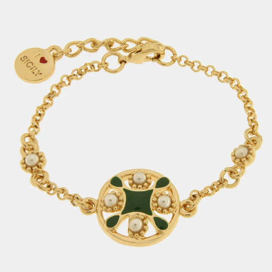 Bracciale in metallo con finitura dorata del marchio BySimon appartenente alla collezione Fiori di Lava caratterizzato da una catenina a maglia rolo e un pendente centrale circolare ispirato alle maioliche mediterranee. Il ciondolo principale presenta una decorazione a croce in smalto verde scuro circondata da quattro perle bianche incastonate in cornici dorate con lavorazione a sbalzo. Il gioiello è rifinito con una chiusura a moschettone, una catenella di regolazione e un piccolo charm terminale rotondo c