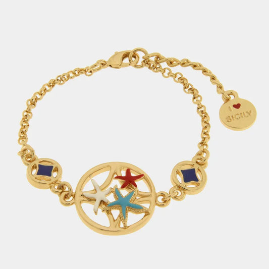 Bracciale in metallo con finitura dorata del marchio BySimon appartenente alla collezione Fiori di Lava caratterizzato da una catenina a maglia rolo e un importante elemento centrale circolare traforato. Il decoro principale racchiude tre stelle marine tridimensionali smaltate nei colori bianco, rosso e azzurro, affiancate lateralmente da due charms tondi dorati con inserti geometrici in smalto blu scuro. Il gioiello è completato da una chiusura a moschettone con catenella di regolazione e un ciondolo termi
