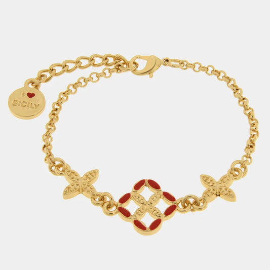 Bracciale in metallo con finitura dorata del marchio BySimon appartenente alla collezione Fiori di Lava caratterizzato da una catenina a maglia rolo con tre ciondoli ispirati alle maioliche siciliane. L'elemento centrale è un quadrifoglio traforato con petali rifiniti in smalto rosso vibrante, affiancato da due charms laterali dorati a forma di fiore con lavorazione a rilievo. Il gioiello è completato da una chiusura a moschettone, una catenella di estensione per regolare la misura e un charm terminale circ
